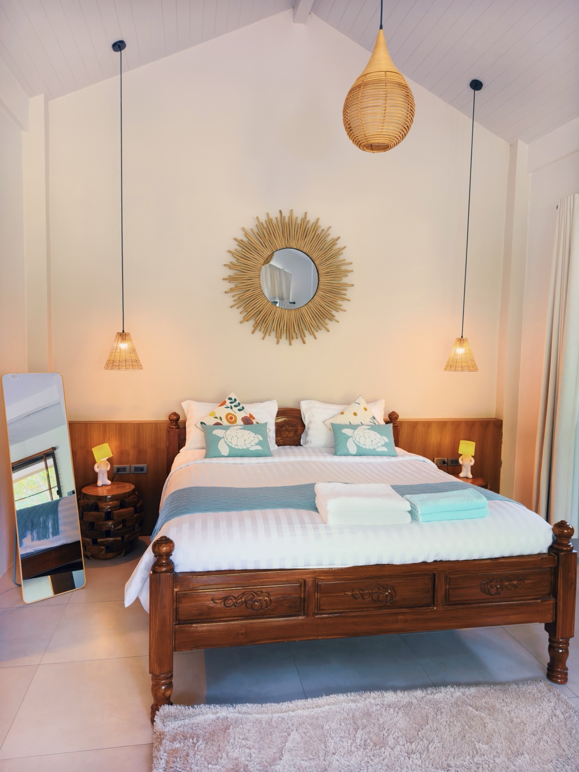 Bungalow B: carved wooden bed, sunburst mirror and rattan pendant lights