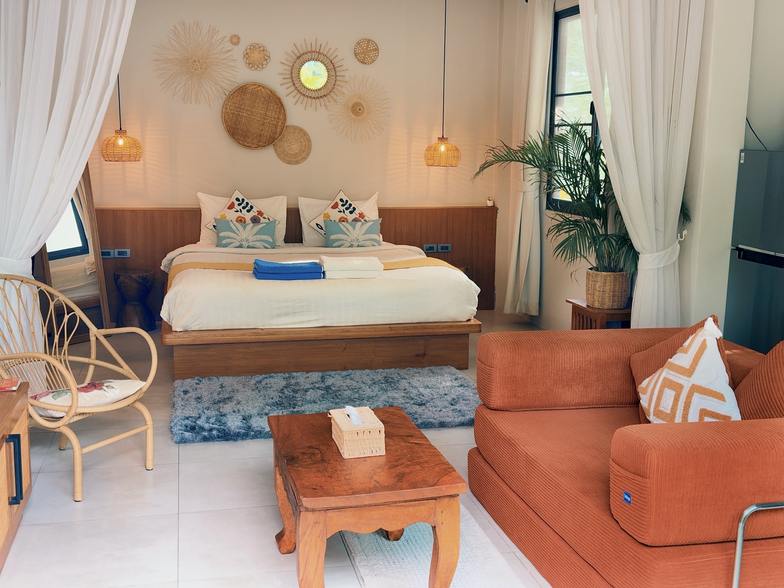 Bungalow A: bedroom with woven wall decorations, low wooden bed and orange sofa