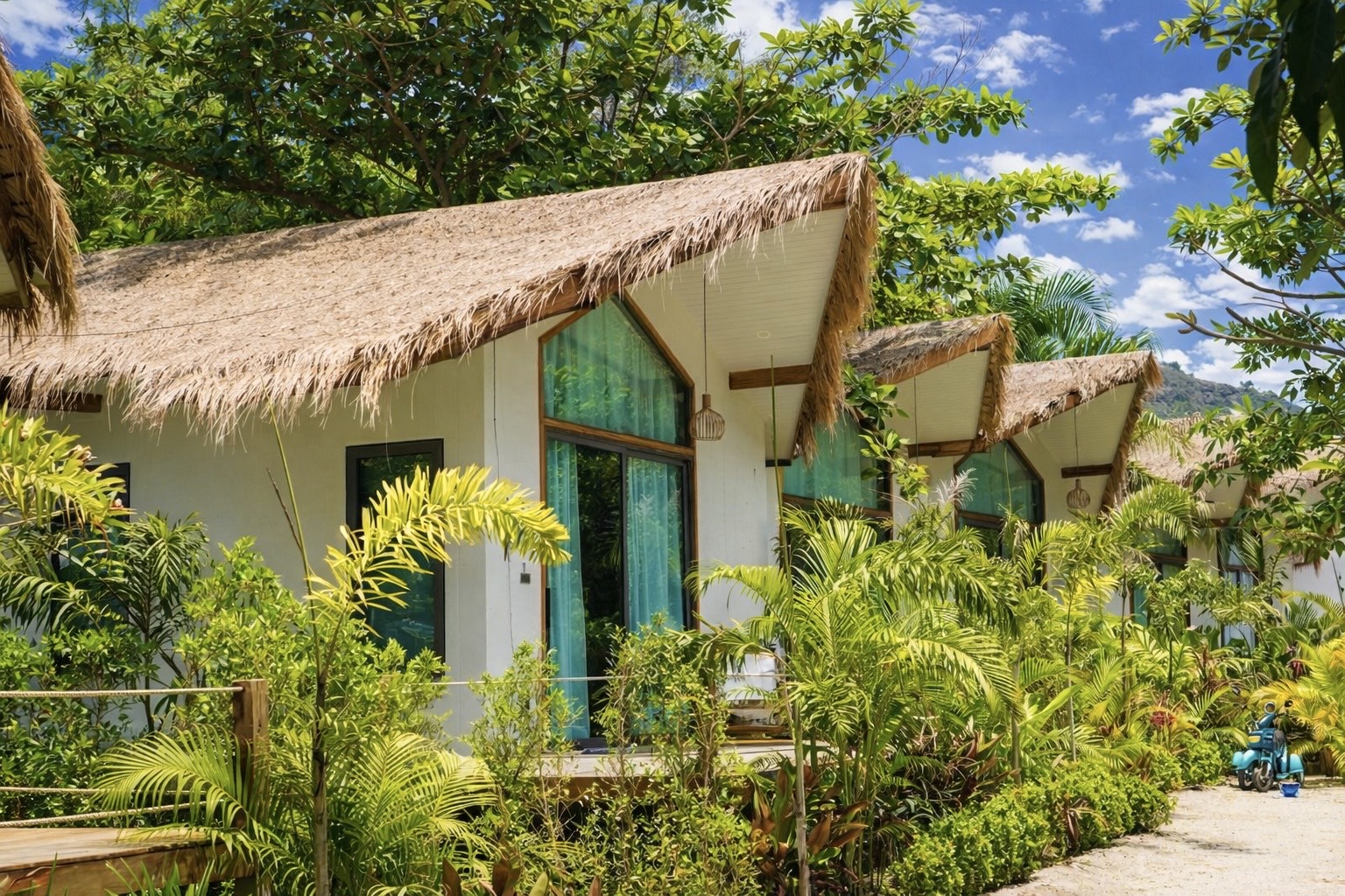 Thatched-roof bungalows among lush tropical gardens in the surrounding complex